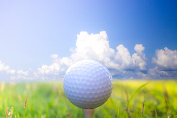 Golf ball placed on grass with sky background.