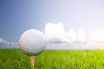 Golf ball placed on grass with sky background.