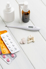 Cold remedies, medicines, thermometer, capsules and pills in a blister pack on wooden table. Healthcare concept, home treatment of flu and coronavirus