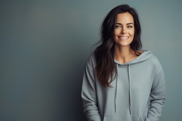 Fototapeta premium Portrait of a glad woman in her 30s sporting a comfortable hoodie against a minimalist or empty room background. AI Generation