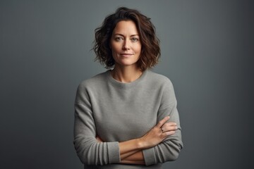 Obraz premium Portrait of a tender woman in her 40s dressed in a warm wool sweater against a minimalist or empty room background. AI Generation