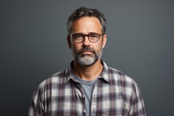 Fototapeta premium Portrait of a content man in his 50s wearing a comfy flannel shirt against a minimalist or empty room background. AI Generation