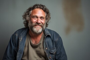 Obraz premium Portrait of a blissful man in his 50s wearing a rugged jean vest against a minimalist or empty room background. AI Generation