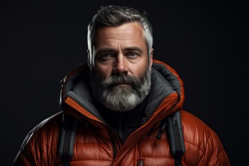 Obraz premium Portrait of a glad man in his 50s donning a durable down jacket against a minimalist or empty room background. AI Generation