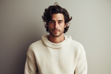 Obraz premium Portrait of a glad man in his 20s dressed in a warm wool sweater against a minimalist or empty room background. AI Generation
