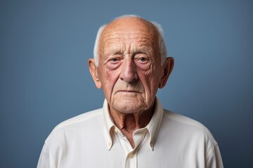 Obraz premium Portrait of a content elderly man in his 90s wearing a simple cotton shirt against a minimalist or empty room background. AI Generation