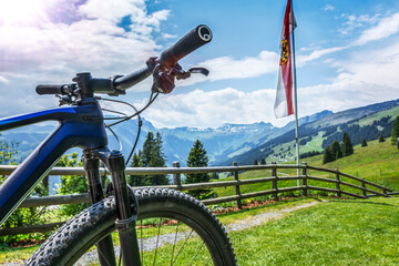 Mountainbike Impression in österreichischen Alpen bei Saalbach mit Salzburger Land Fahne und Landschaft mit Blick auf Berge im Sommer