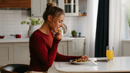Side view of beautiful young woman enjoying healthy food for lunch at the domestic kitchen