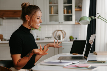 Smiling young female entrepreneur having video call while sitting at the home office