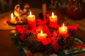 Advent wreath made of pine branches with four burning candles