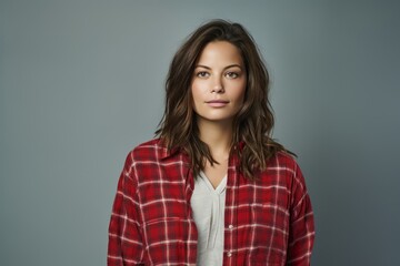 Obraz premium Portrait of a content woman in her 30s wearing a comfy flannel shirt against a blank studio backdrop. AI Generation