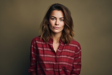 Fototapeta premium Portrait of a content woman in her 30s wearing a comfy flannel shirt against a blank studio backdrop. AI Generation