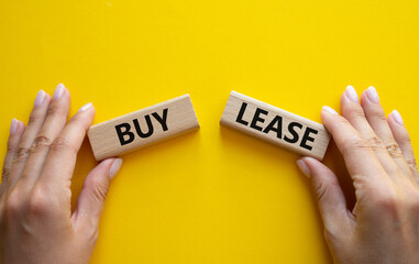 Buy or Lease symbol. Concept word Buy or Lease on wooden blocks. Businessman hand. Beautiful yellow...