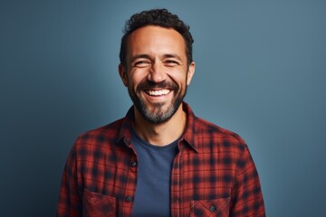 Obraz premium Portrait of a happy man in his 40s dressed in a relaxed flannel shirt against a blank studio backdrop. AI Generation