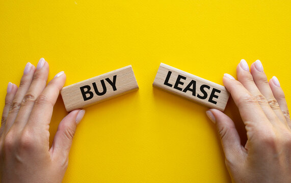 Buy or Lease symbol. Concept word Buy or Lease on wooden blocks. Businessman hand. Beautiful yellow background. Business and Buy or Lease concept. Copy space