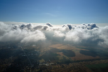Aerial view from airplane window at high altitude of earth covered with white puffy cumulus clouds