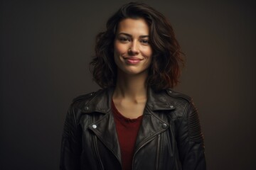 Fototapeta premium Portrait of a tender woman in her 30s sporting a classic leather jacket against a plain cyclorama studio wall. AI Generation