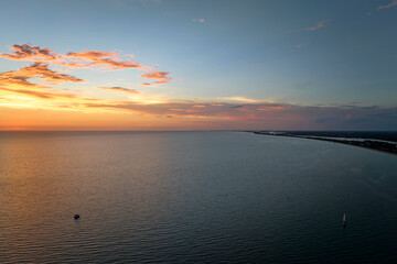 Aerial view of lonesome white yacht at sunset floating on sea waves with ripple surface. Motor boat recreation on ocean surface