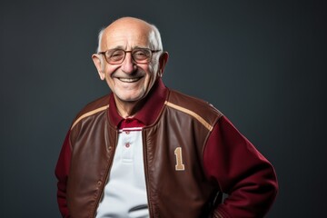 Fototapeta premium Portrait of a cheerful man in his 70s sporting a stylish varsity jacket against a plain cyclorama studio wall. AI Generation
