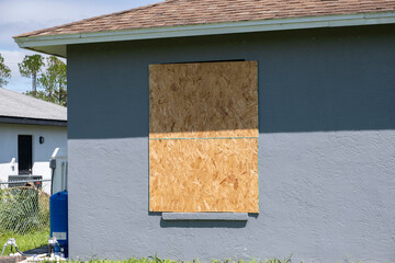 Fototapeta premium Plywood mounted as storm shutters for hurricane protection of house windows. Protective measures before natural disaster in Florida