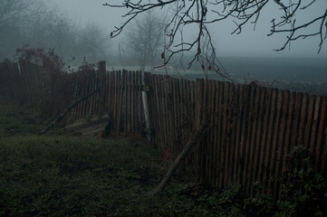 old collapsed wooden fence in the fog