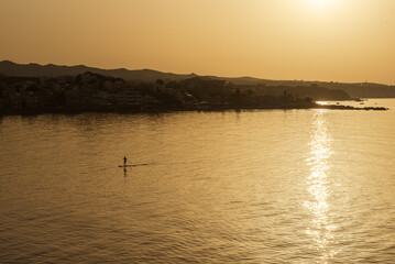 Fototapeta premium The man paddleboarding on sea early sunset