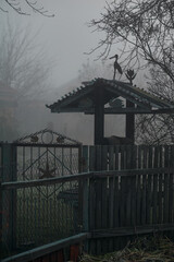 old well in the fog behind an old fence