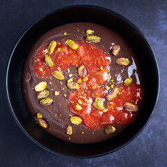 Dunkler Schokoladenpudding mit Erdbeeren-Rhabarber-Grütze und Pistazien. 