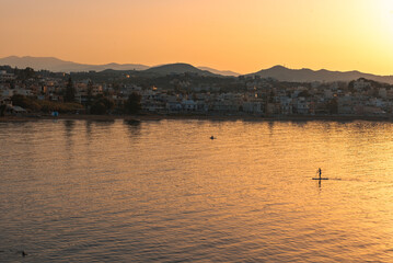 The man paddleboarding on sea early sunset