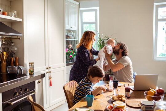 Family , kitchen and parents playing with little baby during breakfast