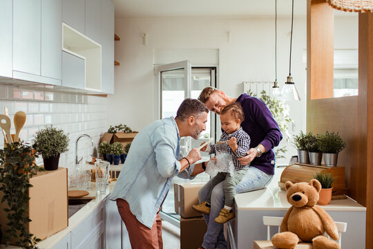 Gay couple enjoying a playful moment with their baby in the kitchen