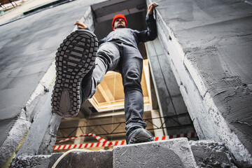 A construction worker steps into an unguarded, dangerous opening at a construction site. Violation of safety regulations at a construction site. - obrazy, fototapety, plakaty