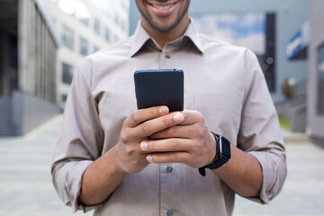 Close up of man's hands, businessman in shirt holding phone, using app on smartphone, walking in city outside office building.
