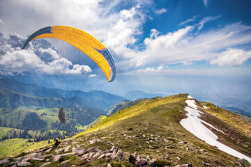 Paraglider is planning in the sky in a picturesque hilly area.