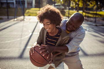 Father and Son Enjoying a Game of Basketball Outdoors