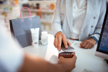 Close up of customer makes a digital payment at a pharmacy counter