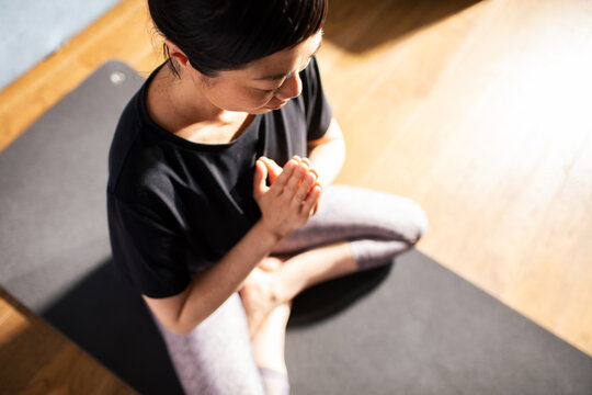 Japanese woman practicing meditation in a sunlit room