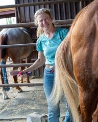 A woman brushing her horse tail