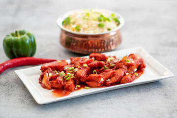 Delicious Sticky honey-soy ginger chicken on plate over dark stone background