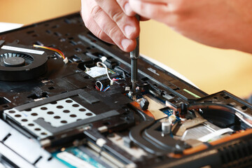 Repaiman with screwdriver fixing disassembled laptop parts. Technical support and fixing gadgets...