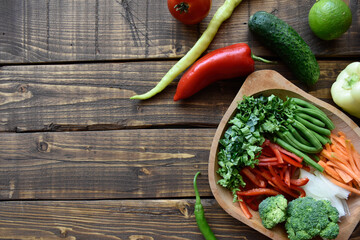 Fresh vegetables mix chopped on a wooden table background. Kale leaves, green beans, peppers,...