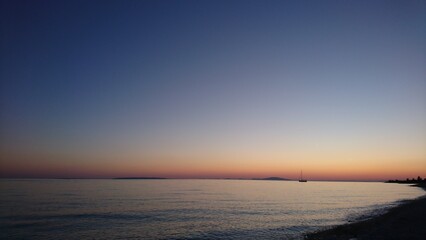 Boat in the distance and orange sunset in the evening