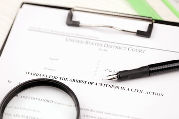 District court warrant for the arrest of a witness in a civil action papers on A4 tablet lies on...