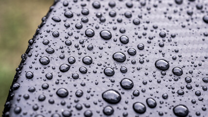 Rain droplets or water splashing and floating drop on the black bonnet of car with Kevlar films sticker at the night, waterproof abstract background. Monochrome texture.