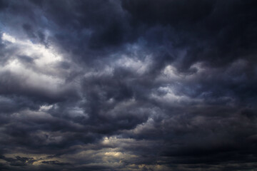 Epic Storm sky with many dark grey black cumulus rainy clouds against blue sky background texture,...