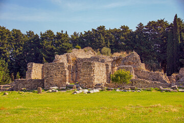 Fototapeta na wymiar Part of a greek ruin on the greek island kos with green grass and a blue 