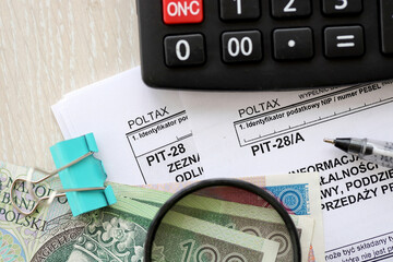 Information of income of inherited enterprise PIT28 and PIT-28A tax forms on accountant table with pen and polish zloty money bills close up