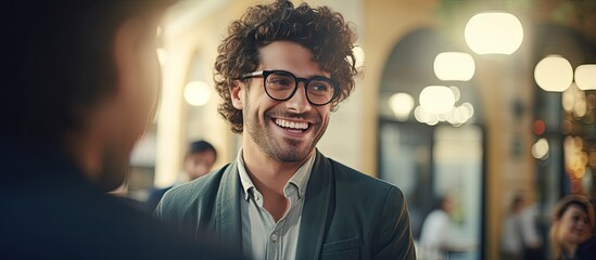 The stylish Italian man, sporting fashionable glasses, looks up with a smile as he finds himself in a close and happy interaction with the eye doctor in the education-filled interior, showcasing his - obrazy, fototapety, plakaty