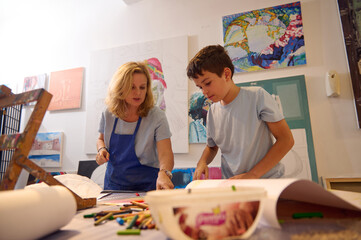 Fototapeta premium Authentic portrait of art school student boy and female artist painter teacher during painting lesson. Visual art class