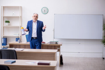 Old male teacher holding megaphone in the classroom